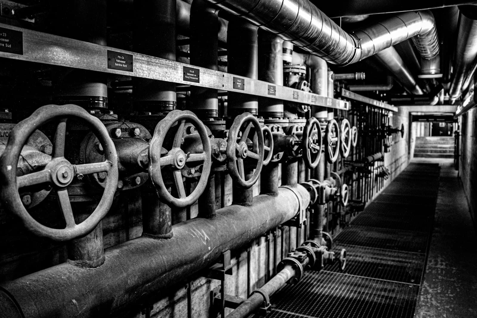 A corridor of industrial pumps, valves, and pipework inside a pump station