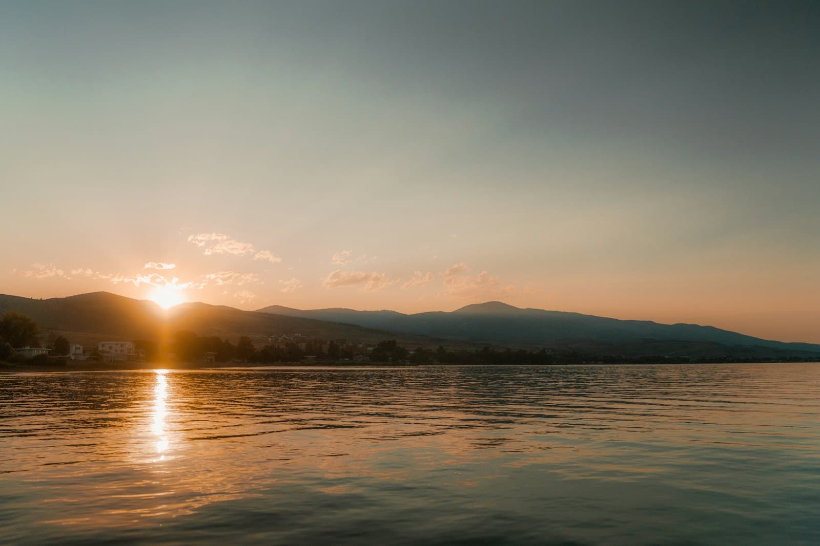 Sunrise over a calm reservoir lake with mountains on the horizon